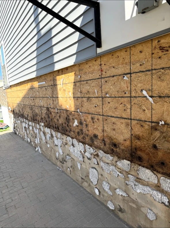 Before: exposed lower-wall sheathing during siding work